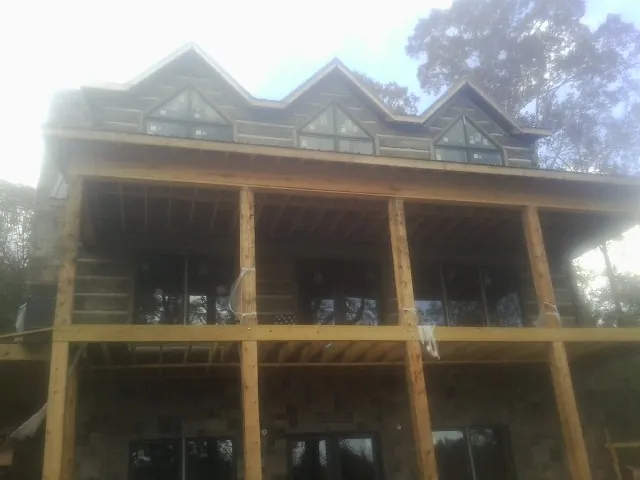 Dormers and porch framing on a large log home under construction — Roof Coating work by our crew in River Falls