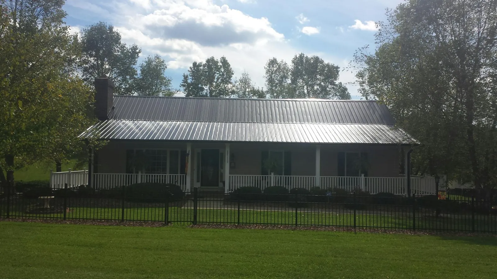 Gray metal roof on a brick ranch with a full width front porch — Gutter Guard Installation work by our crew in River Falls