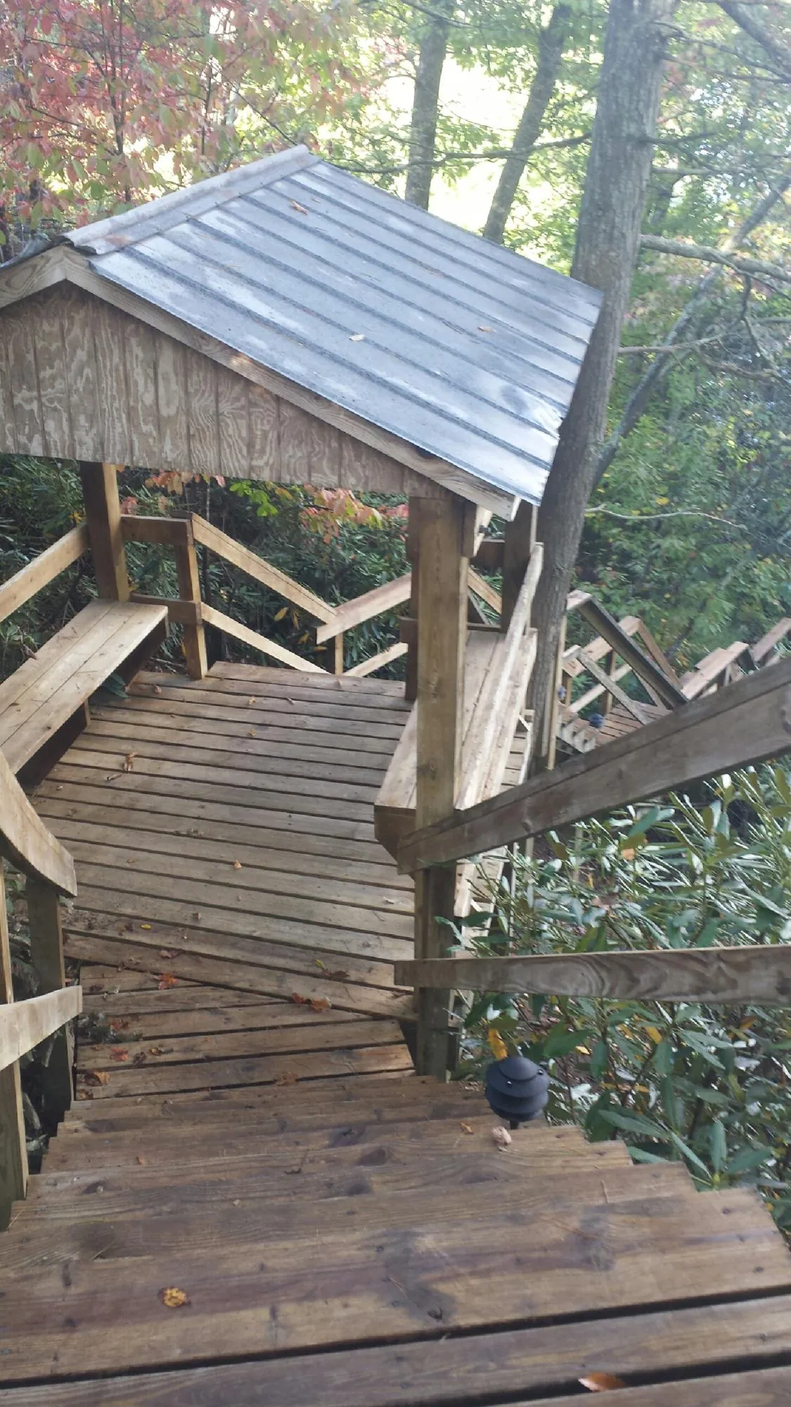 Metal roofed shelter over wooden steps on a wooded walkway — Skylight Repair & Installation work by our crew in River Falls